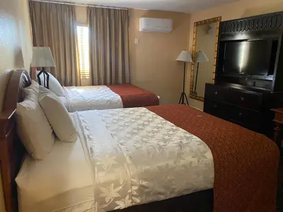 a hotel room with two beds and a flat screen tv at The Lemon Tree Hotel in Anaheim