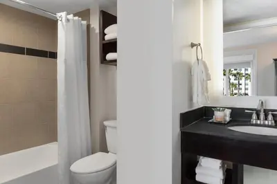 a bathroom with a toilet and a sink and a tub at Peacock Suites in Anaheim