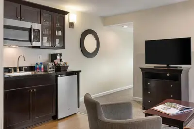 a living room with a kitchen and a tv at Peacock Suites in Anaheim