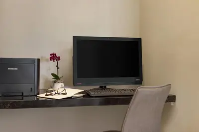 a desk with a computer and a monitor and a chair at Peacock Suites in Anaheim