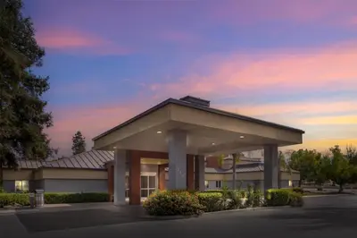 a large building with a sunset in the background at Best Western Porterville Inn in Porterville