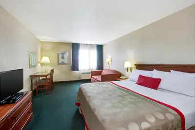 a hotel room with a bed and a flat screen tv at Ramada by Wyndham Hawthorne/LAX in Hawthorne
