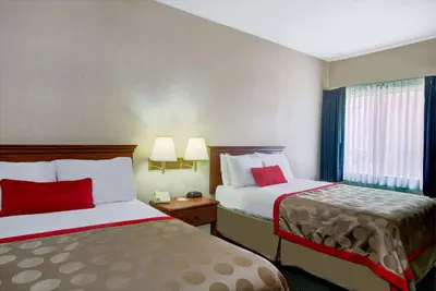 a hotel room with two beds with red pillows at Ramada by Wyndham Hawthorne/LAX in Hawthorne