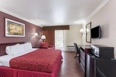 a hotel room with a bed and a flat screen tv at Hospitality Inn in San Bernardino