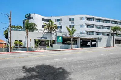 an empty street in front of a building with palm trees at Quality Inn & Suites Hermosa Beach in Hermosa Beach