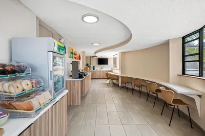 a cafeteria with a refrigerator and tables and chairs at Quality Inn & Suites Hermosa Beach in Hermosa Beach