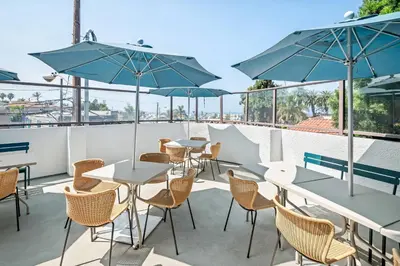 a patio with tables and chairs and umbrellas at Quality Inn & Suites Hermosa Beach in Hermosa Beach