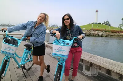 two women are standing with their bikes on a dock at People's Choice Central Location Prkg & Patio LBD in Long Beach