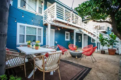 a patio with a table and chairs in front of a blue building at People's Choice Central Location Prkg & Patio LBD in Long Beach