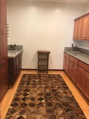 a kitchen with wooden cabinets and a table and a rug at Luxurious 3 BD in Culver City with POOL &HOT SPA in Los Angeles