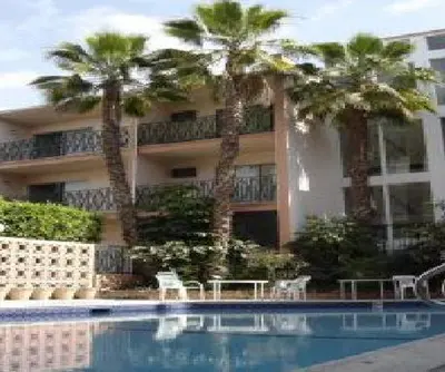 a building with palm trees in front of a swimming pool at Royal Century Hotel at LAX in Inglewood