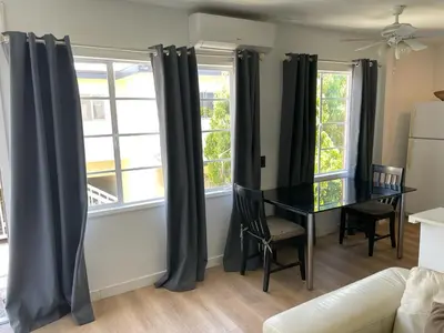 a living room with a table and two windows at Renovateed Two-Bedroom Apartment in Santa Monica in Los Angeles
