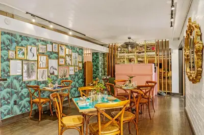a restaurant with tables and chairs and a wall with paintings at The Hollywood Roosevelt in Los Angeles