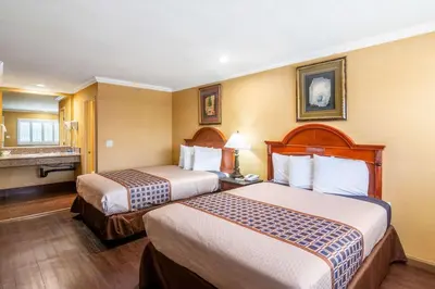 a hotel room with two beds and a bathroom at Rodeway Inn Artesia Cerritos in Artesia
