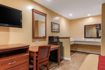 a hotel room with a desk and a tv and a bathroom at Rodeway Inn Carson - Los Angeles South in Carson