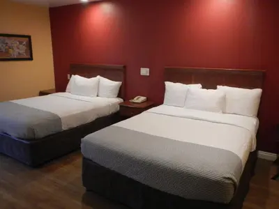 two beds in a hotel room with red walls at Rodeway Inn Carson - Los Angeles South in Carson