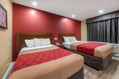 a hotel room with two beds and a red wall at Rodeway Inn Carson - Los Angeles South in Carson
