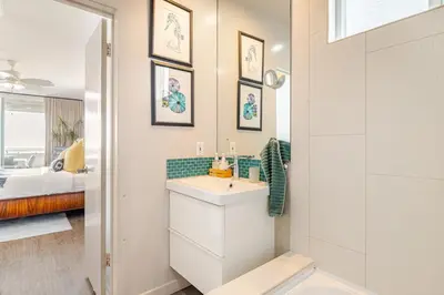 a bathroom with a sink and a mirror and a bed at Oceanfront Oasis in Long Beach