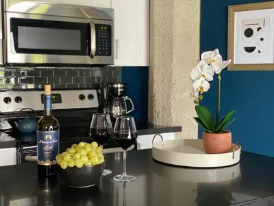 a kitchen with two glasses of wine and grapes on a counter at THE MIDNIGHT LOFT BY BOBOU DESIGN (KING SUITE) in Los Angeles