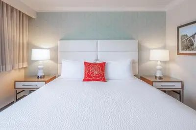 a bedroom with a white bed with a red pillow at Pasadena Rose & Crown Hotel in Pasadena
