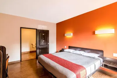 a bedroom with a bed with an orange wall at Motel 6 Bell Gardens, CA - Los Angeles in Bell Gardens