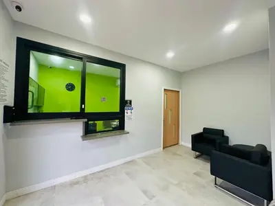 a waiting room with a black couch and a window at Deluxe Inn Hawthorne/ LAX in Hawthorne