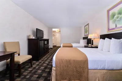 a hotel room with two beds and a desk and chair at Quality Inn & Suites Montebello - Los Angeles in Montebello