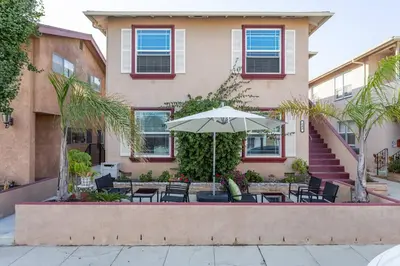 a patio with chairs and an umbrella in front of a building at New Belmont Shore Retreat with free Parking Walk to Beaches in Long Beach