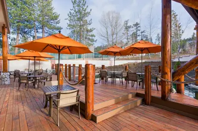 a wooden deck with tables and chairs with umbrellas at Holiday Inn Resort The Lodge at Big Bear Lake by IHG in Big Bear Lake