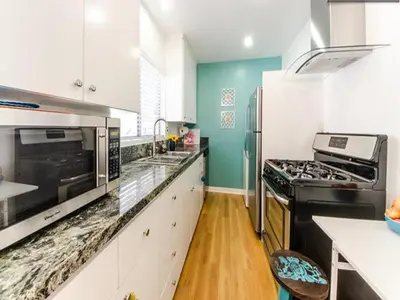 a kitchen with white cabinets and black appliances at Venice Beach Apartments Monthly rents in Los Angeles