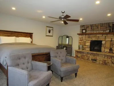a bedroom with a bed and two chairs and a fireplace at Monticello in Big Bear Lake