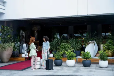 two women standing in front of a building with potted plants at SLS Hotel, a Luxury Collection Hotel, Beverly Hills in Los Angeles
