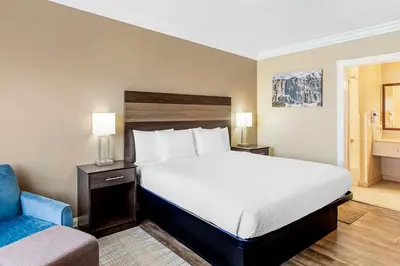a bedroom with a large bed and a blue chair at Best Western China Lake Inn in Ridgecrest