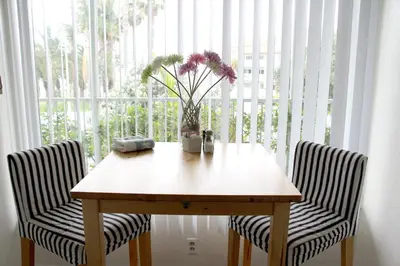 a wooden table with two chairs and a vase with flowers at Bayside Hotel in Los Angeles