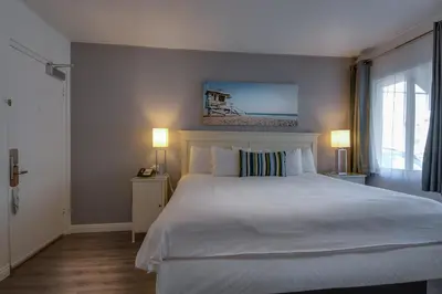 a bedroom with a large white bed and two lamps at Bayside Hotel in Los Angeles