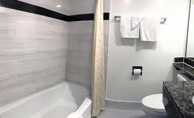 a white bathroom with a tub and a toilet at Starlight Inn Canoga Park in Canoga Park