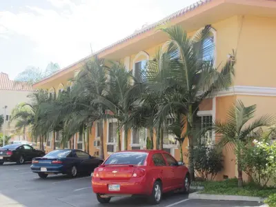 a red car parked in front of a building with palm trees at Starlight Inn Canoga Park in Canoga Park