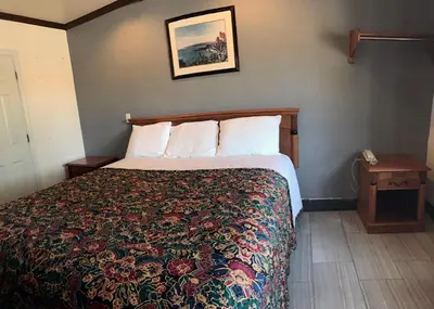 a hotel room with a bed with a floral bedspread at Starlight Inn Canoga Park in Canoga Park