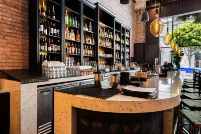 a bar with a counter and a shelf of alcohol at The O Hotel, Trademark Collection by Wyndham in Los Angeles