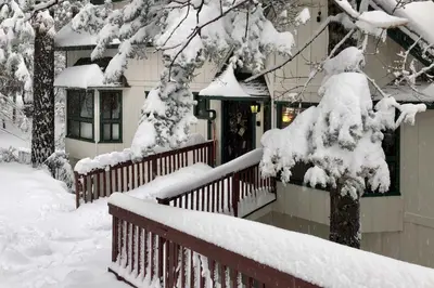 a house covered in snow with a fence at Spacious Lake Arrowhead Home with 2 Decks and Views in Lake Arrowhead