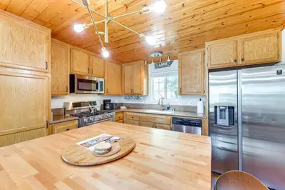 a kitchen with wooden cabinets and a wooden table at Remodeled Crestline Retreat Walk to Lake Gregory! in Crestline