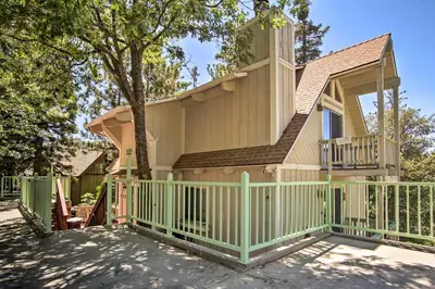 a house with a green fence and a balcony at 5 Mi to Lake Arrowhead Village Cabin with Game Room in Lake Arrowhead