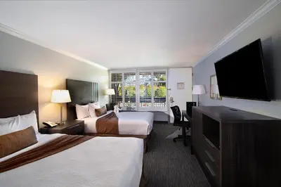 a hotel room with two beds and a flat screen tv at Palm Garden Hotel in Thousand Oaks