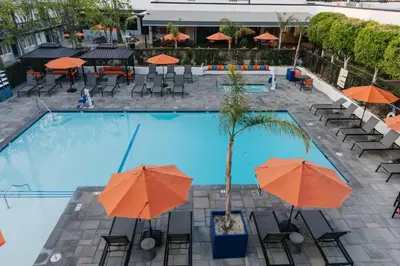 an overhead view of a swimming pool with orange umbrellas at Palm Garden Hotel in Thousand Oaks