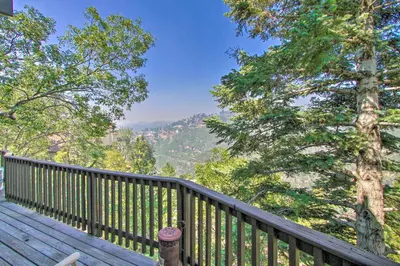a wooden deck with a view of the mountains at Family Cabin with Game Room Near Hiking and Skiing! in Lake Arrowhead