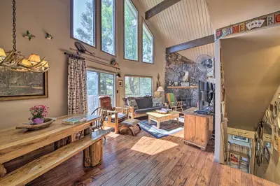 a living room with wooden floors and a large window at Family Cabin with Game Room Near Hiking and Skiing! in Lake Arrowhead