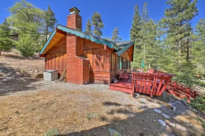 a cabin in the woods with a red fence at Big Bear Lake Cabin with Deck about 7 Mi to Ski Slopes! in Fawnskin