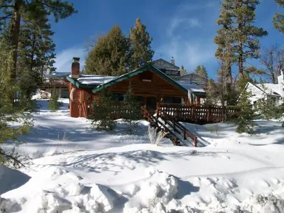 a log cabin in the snow with a fence at Big Bear Lake Cabin with Deck about 7 Mi to Ski Slopes! in Fawnskin
