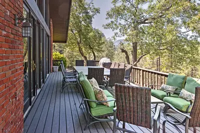 a deck with chairs and tables on a house at Lake Arrowhead House with Lake Views and Wet Bar! in Lake Arrowhead