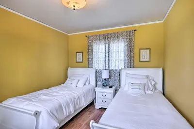 two beds in a bedroom with yellow walls and a window at The Castle Hacienda Heights Home with Patio and Pool in Hacienda Heights